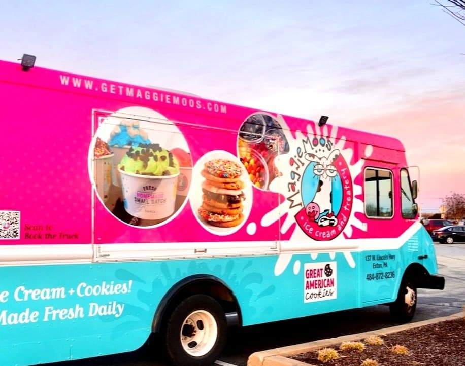 The serving window side of the truck, with the Maggie Moo's logo splat, cups of ice cream, and stacked cookies